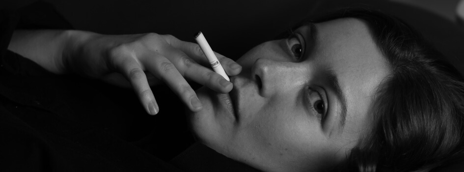 black and white photo of woman holding cigarette in mouth