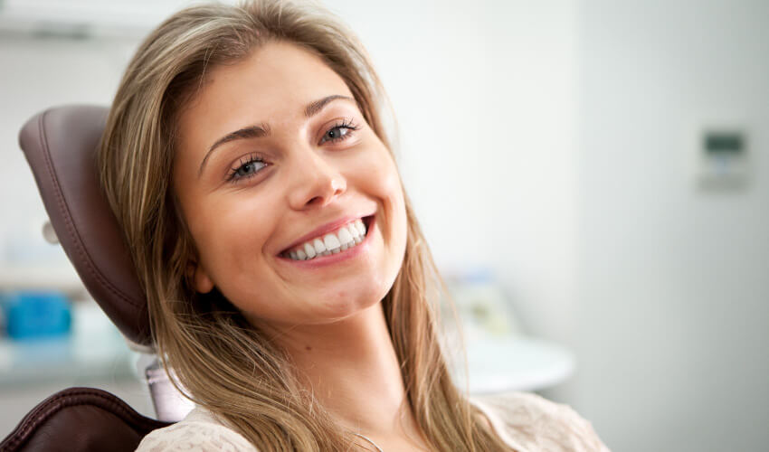 Brunette woman smiles in a dental chair after a CEREC dental crown procedure at Springs Village Dentistry