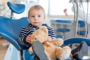 Toddler boy in the dental chair with his teddy bear for his first visit to the dentist.