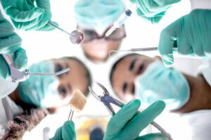 Masked dental professionals preparing for wisdom tooth extraction.