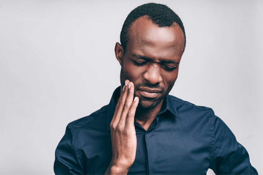 Man holding his hand to his cheek because of a toothache.