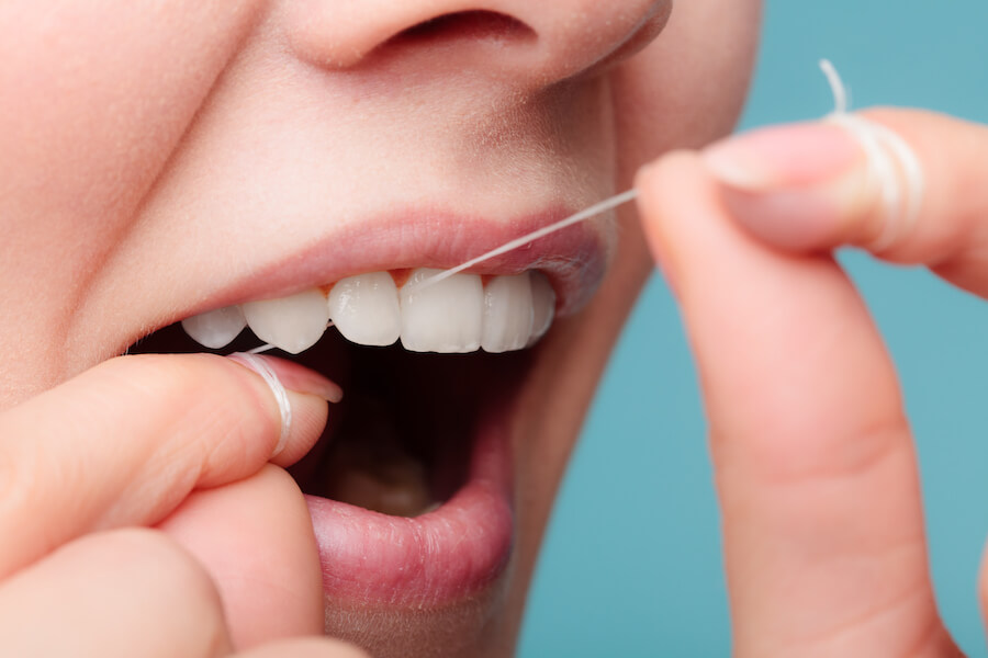Oral hygiene and health care. Smiling women using dental floss white healthy teeth.